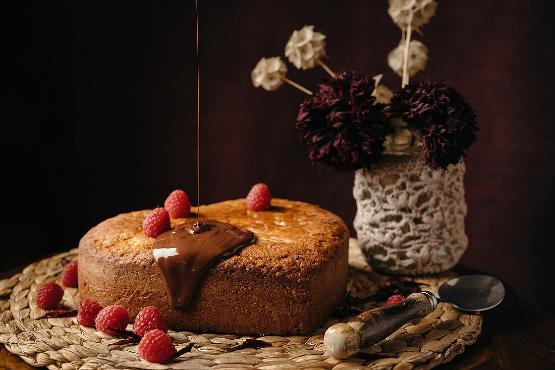 Appetizing homemade cake with fresh berries being poured with chocolate topping