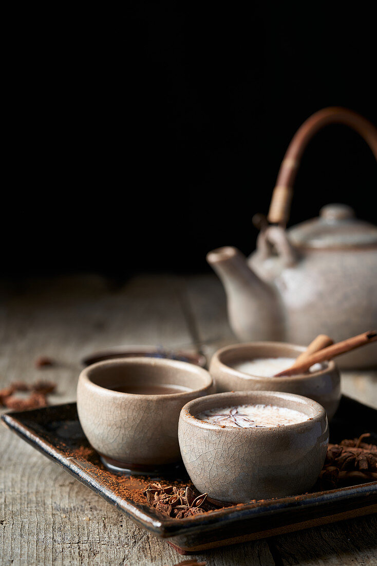 Masala Chai in Keramikschalen mit Sternanis und Zimtstangen