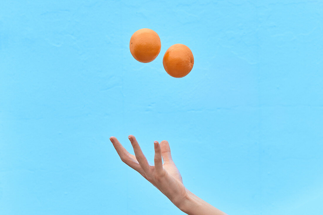 Frau wirft frische Orangen in die Luft