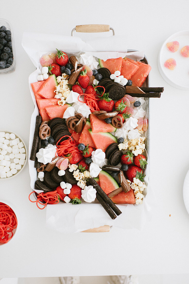 Platte mit Erdbeeren, Wassermelone, Popcorn und Keksen für eine Party