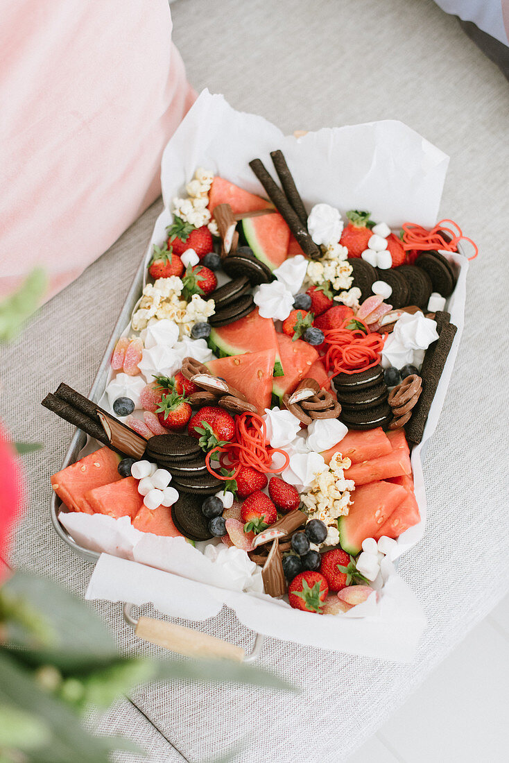 Platte mit Erdbeeren, Wassermelone, Popcorn und Keksen
