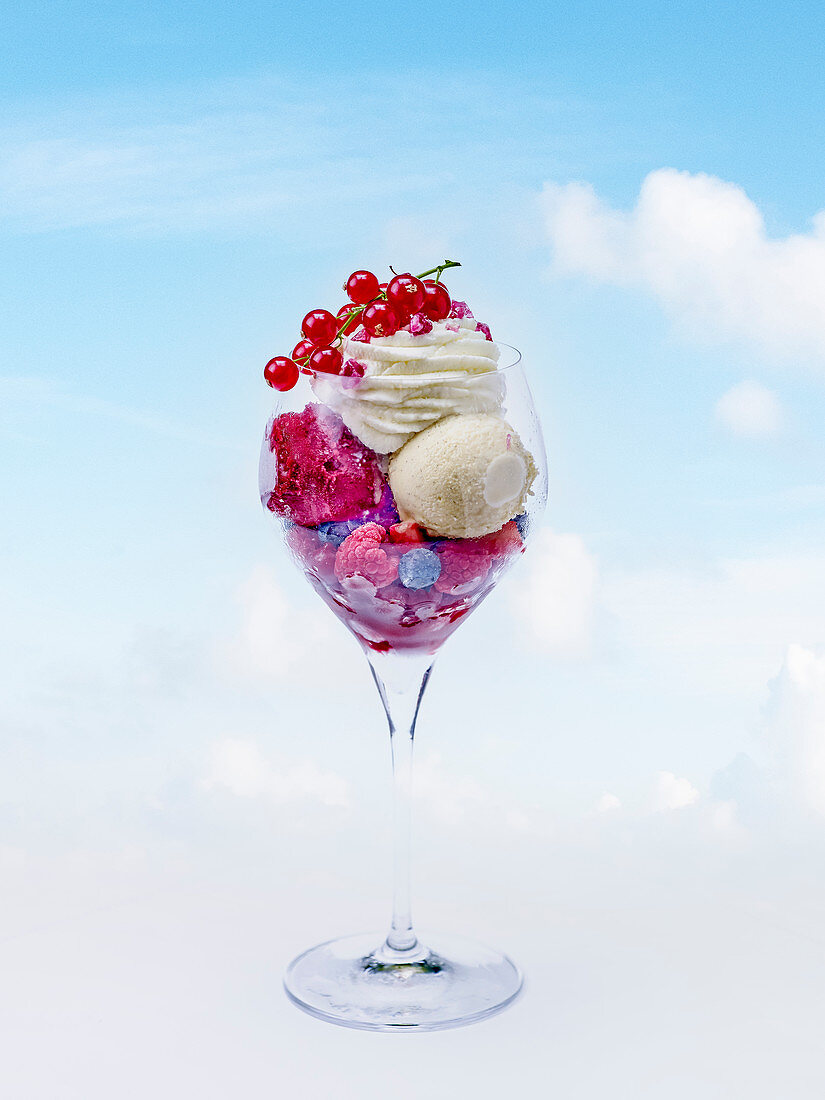 Ice cream sundae with berry ice cream, vanilla ice cream, whipped cream and fresh berries