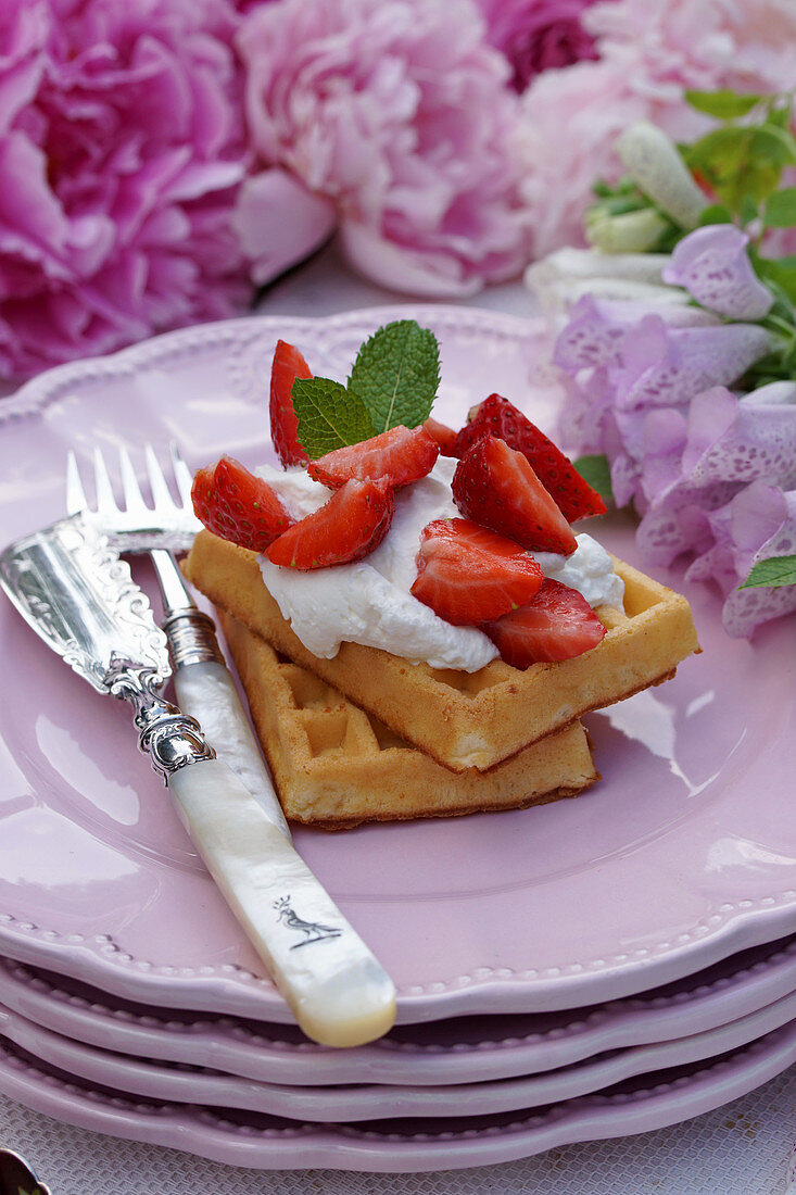 Waffles with strawberries, cream and mint leaves