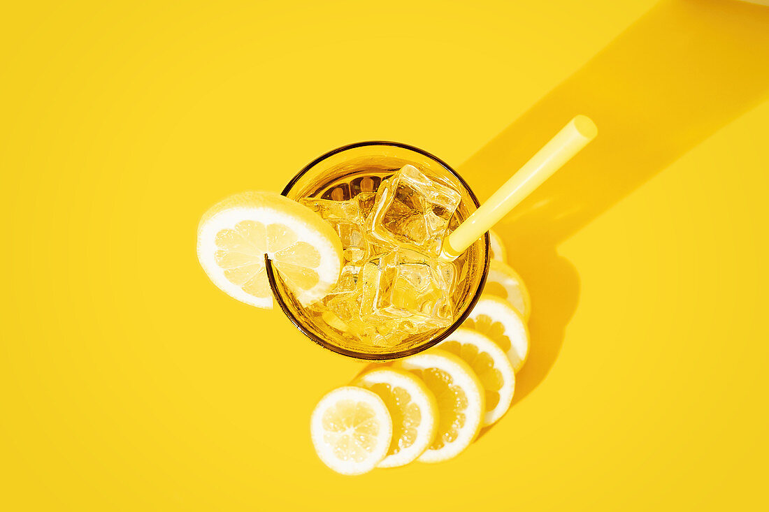 Glass of fresh beverage with lemons placed on table