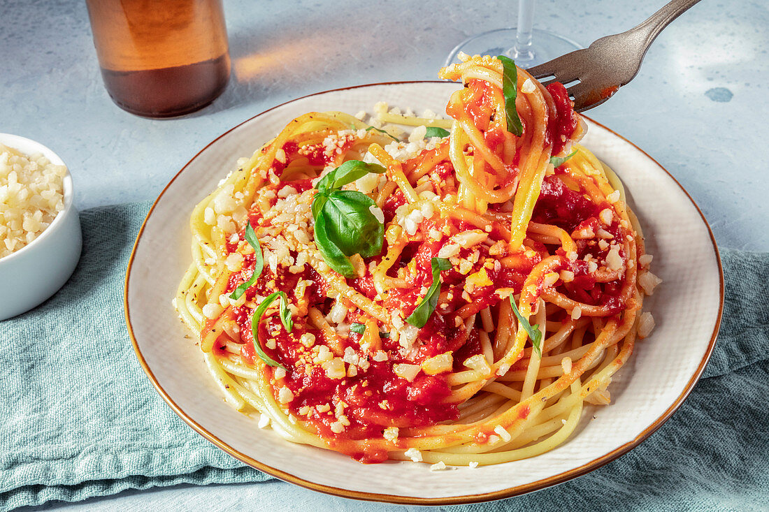 Spaghetti mit Tomatensauce, Käse und Basilikum auf Gabel wickeln