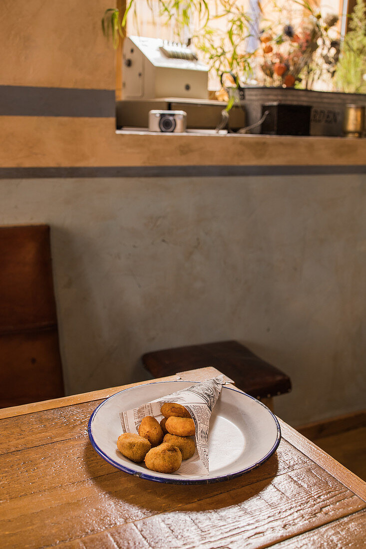 Potato croquettes on plate placed on wooden table in cafeteria