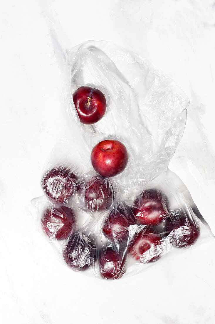 Ripe red cherry berries in transparent plastic sack placed on white table