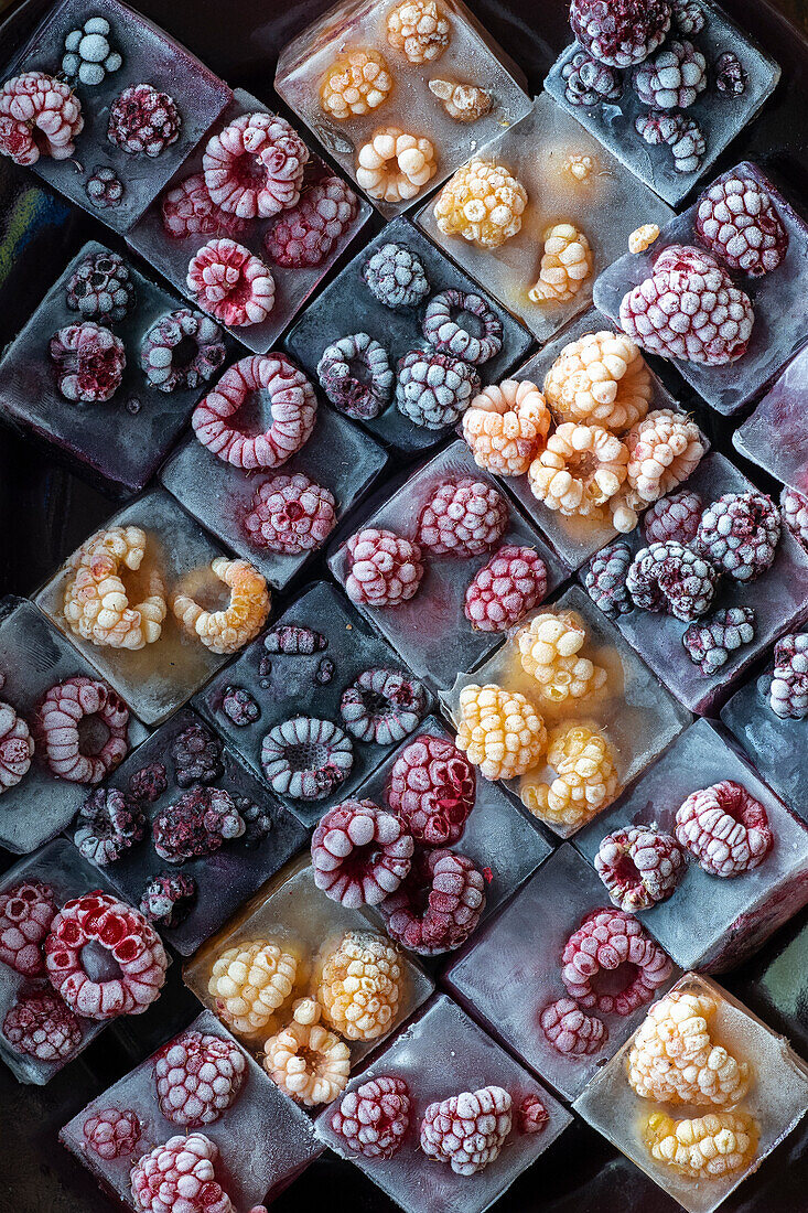 Eiswürfel mit verschiedenfarbigen Himbeeren