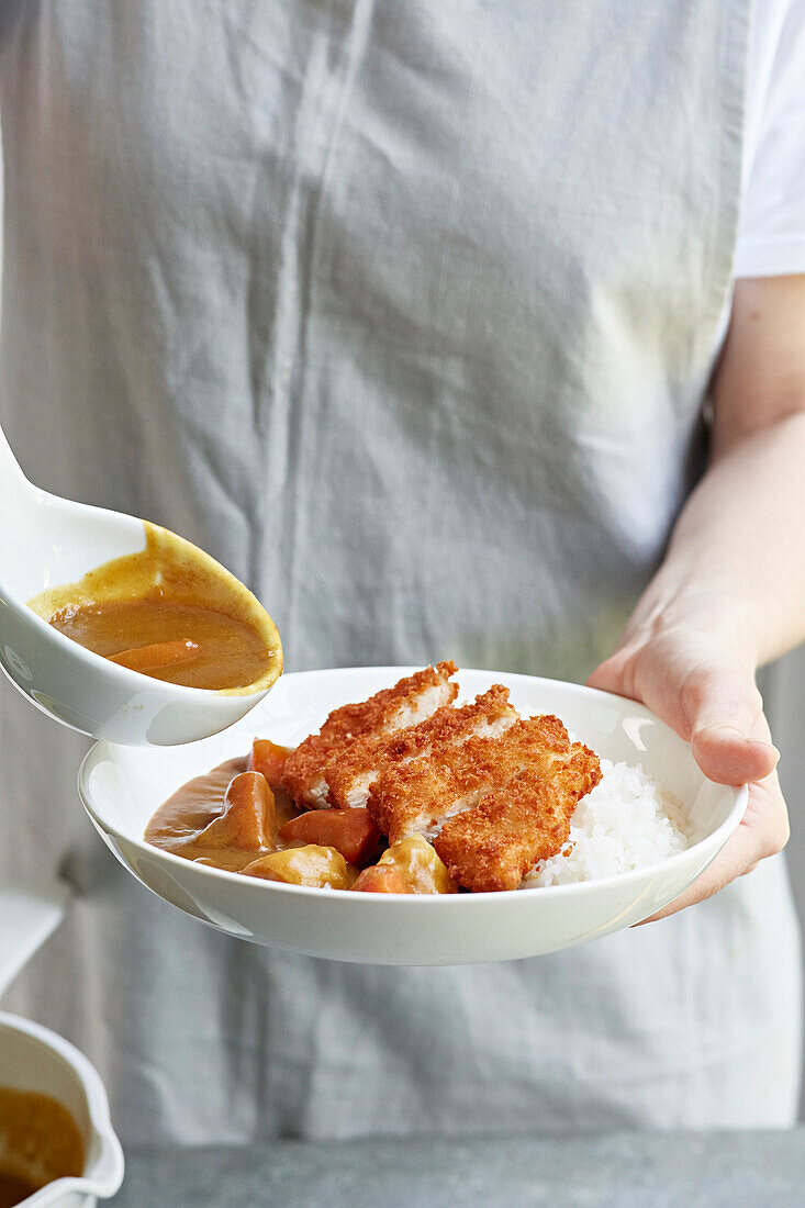 Currysauce über Hähnchen-Katsu geben