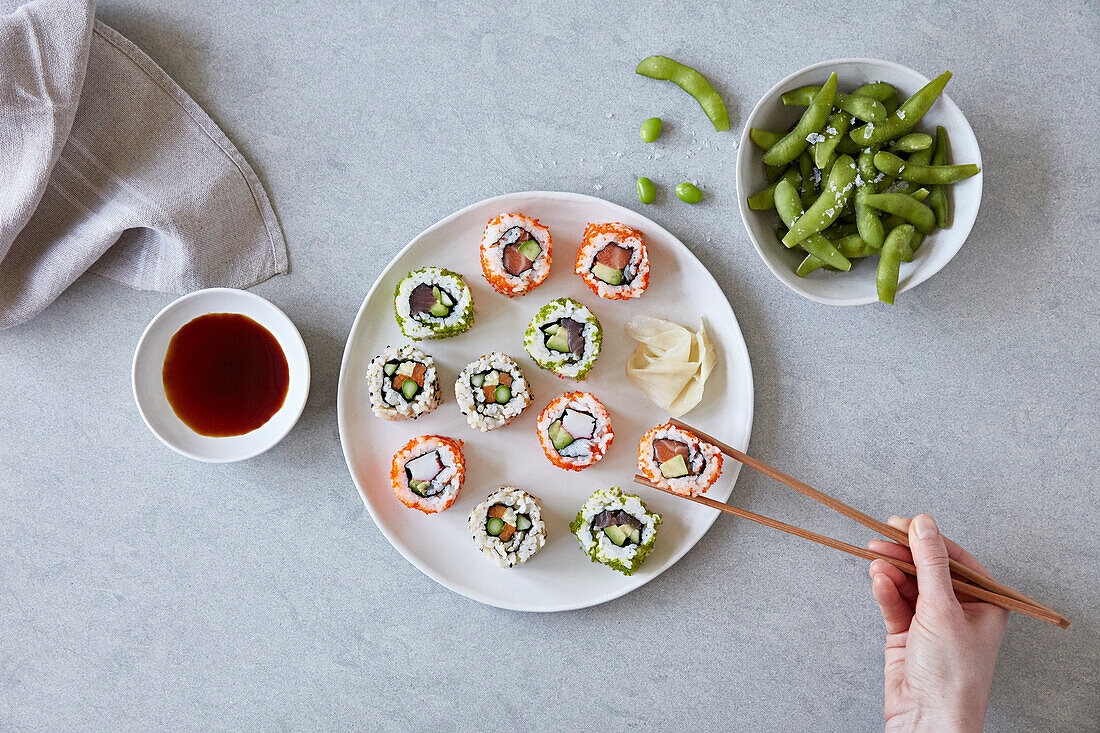 Mixed sushi platter with chopsticks and edamame