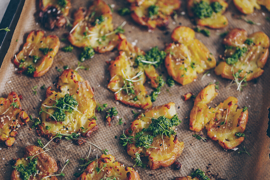Crispy tray-baked squashed potatoes with wild garlic and rocket pesto