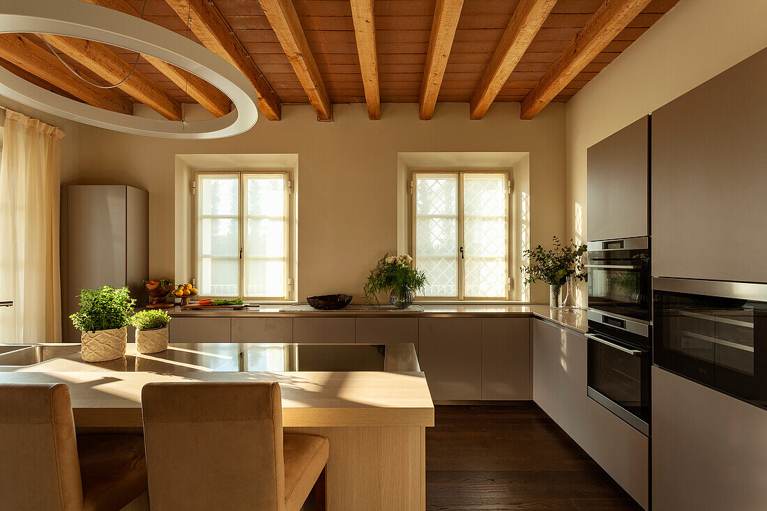 A kitchen with built-in appliances and a counter with chairs