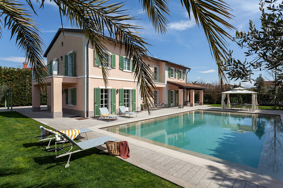 Sonnenliegen am Pool, im Hintergrund Villa mit grünen Fensterläden