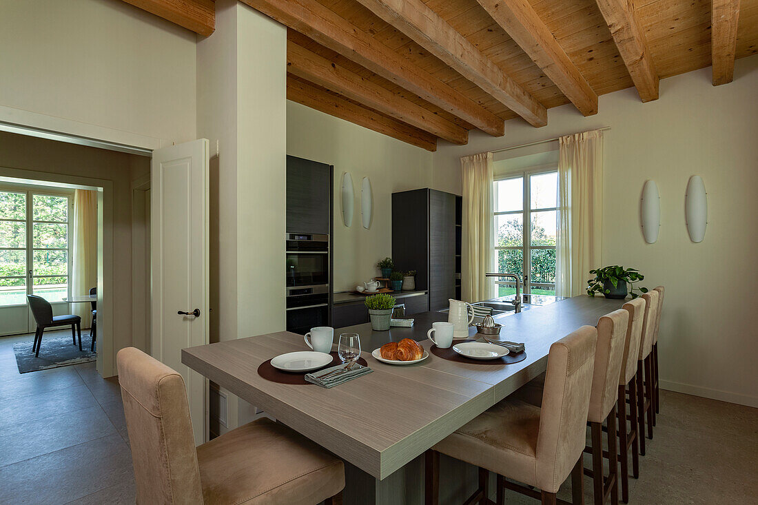 A kitchen counter with an adjacent breakfast table and upholstered chairs