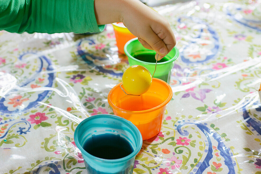 Child coloring Easter Egg with Yellow Dye