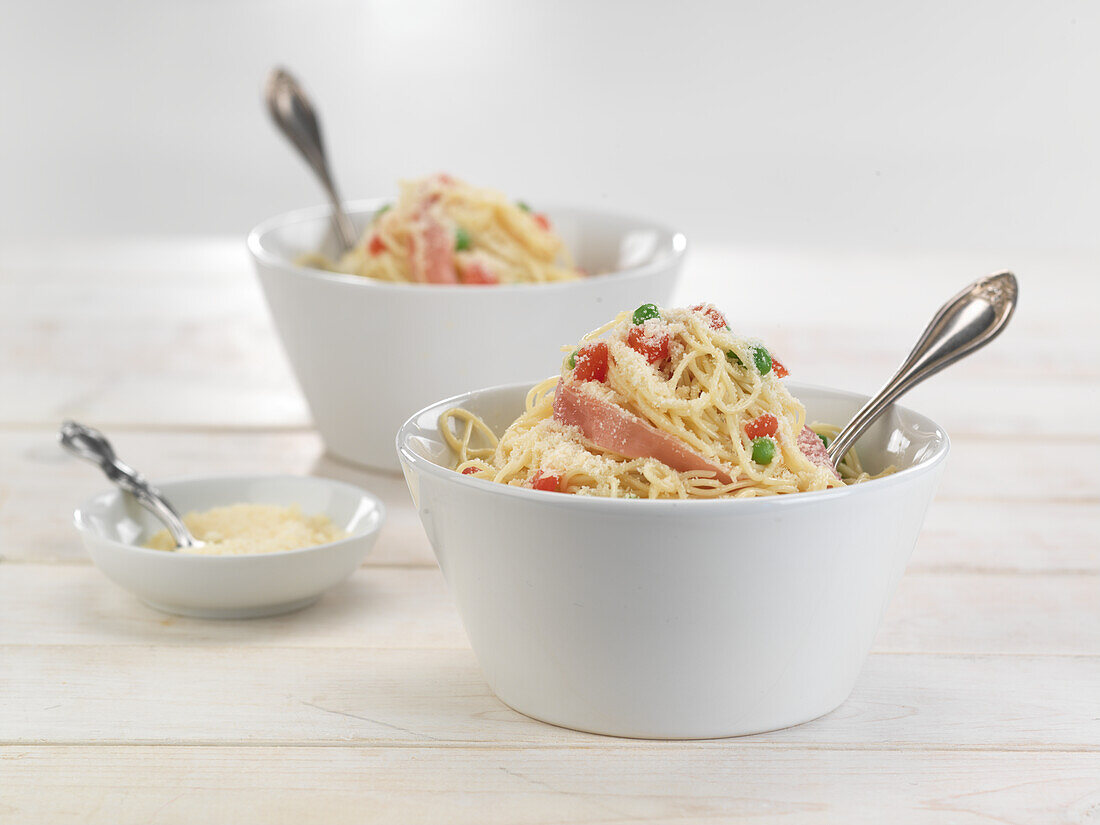 Spaghetti with ham, peas, tomatoes, and Parmesan cheese
