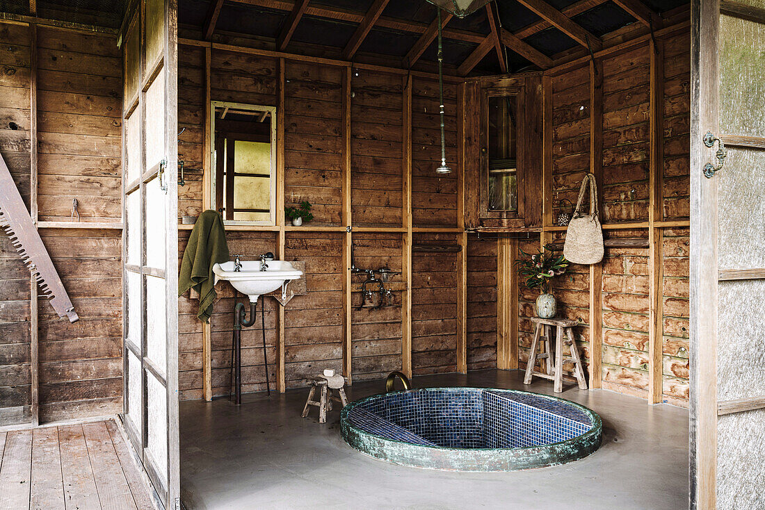 Becken aus recyceltem Pferdetrog mit blauen Mosaikfliesen im Badehaus