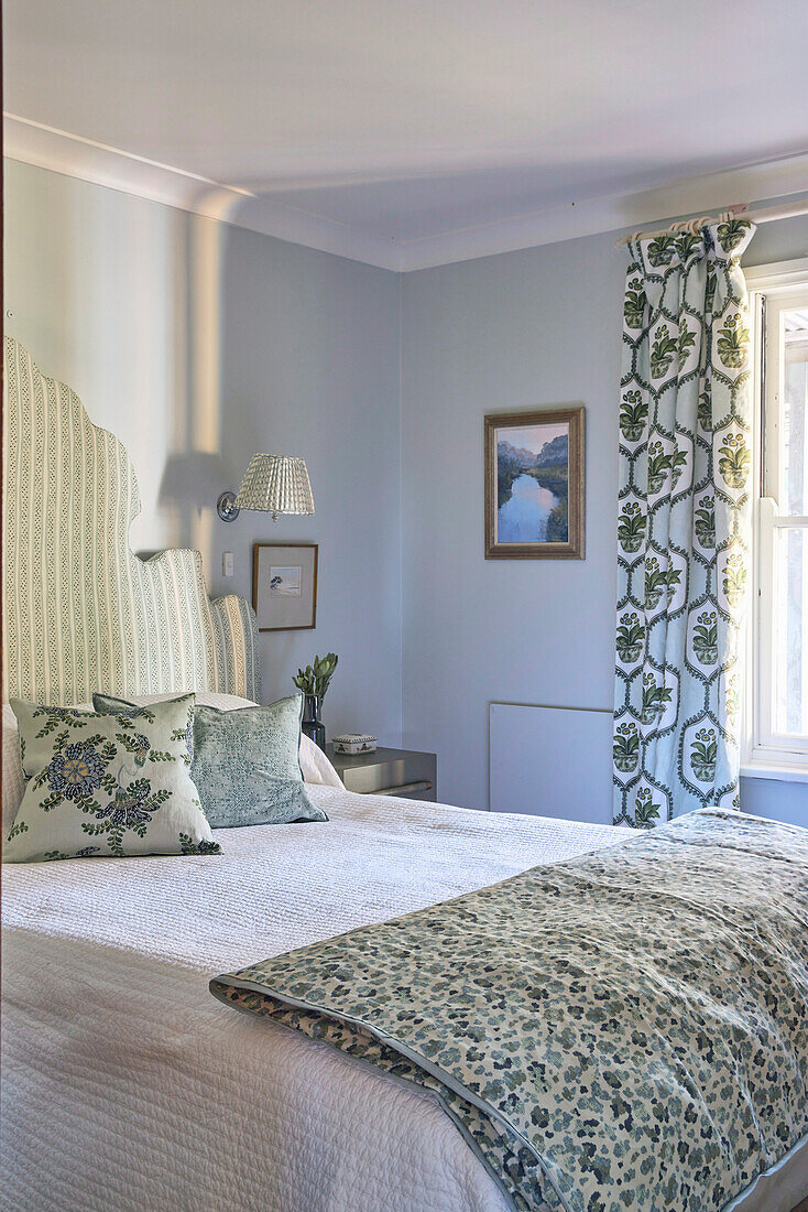 Double bed with high headboard in light blue bedroom