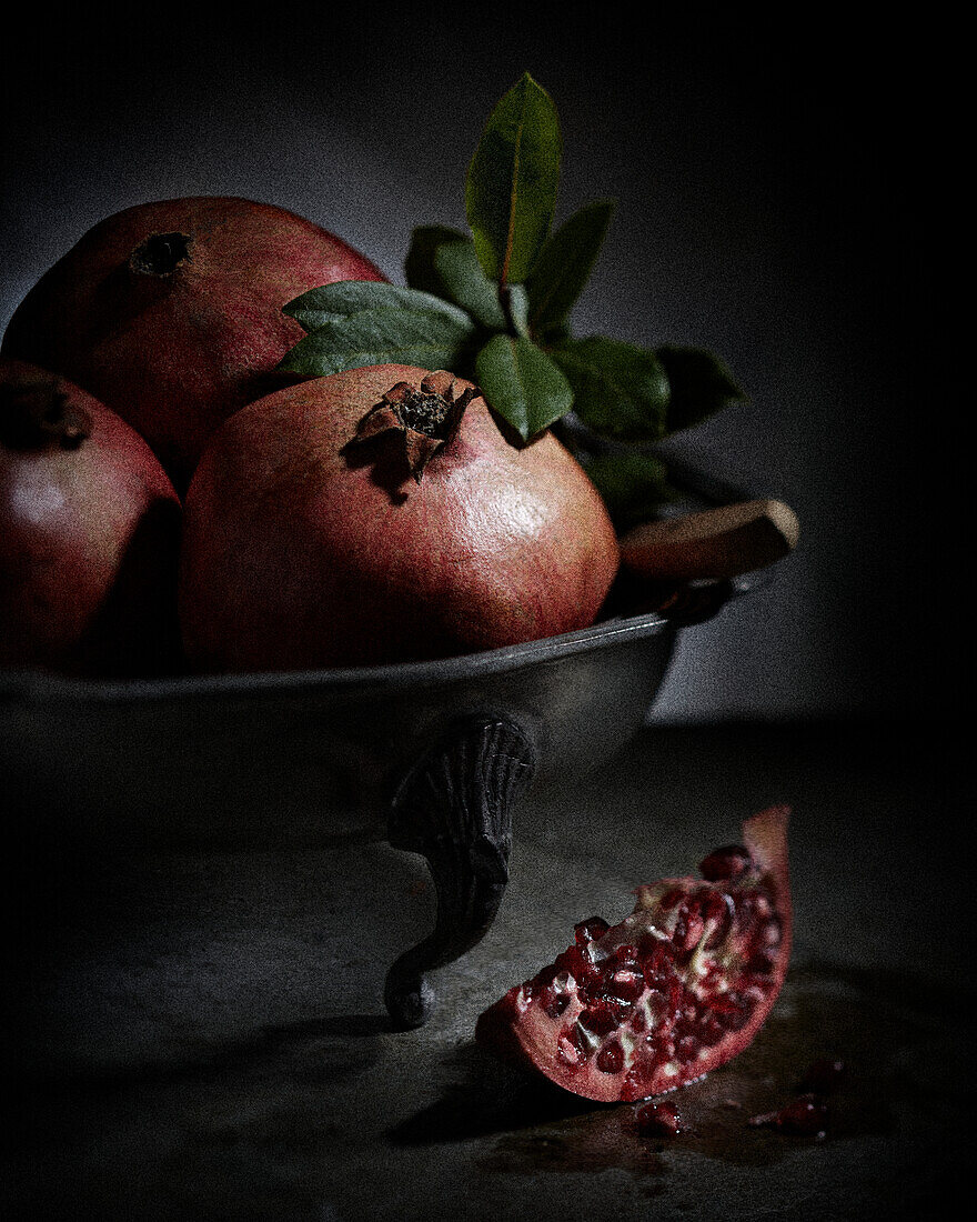 An arrangement of pomegranates in a metal bowl