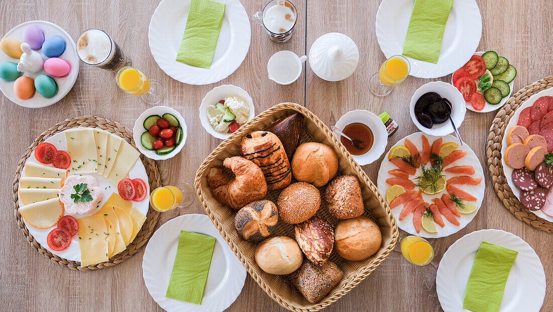 Osterfrühstückstisch mit bunten Eiern, Brötchen, Lachs, Käse- und Wurstplatte