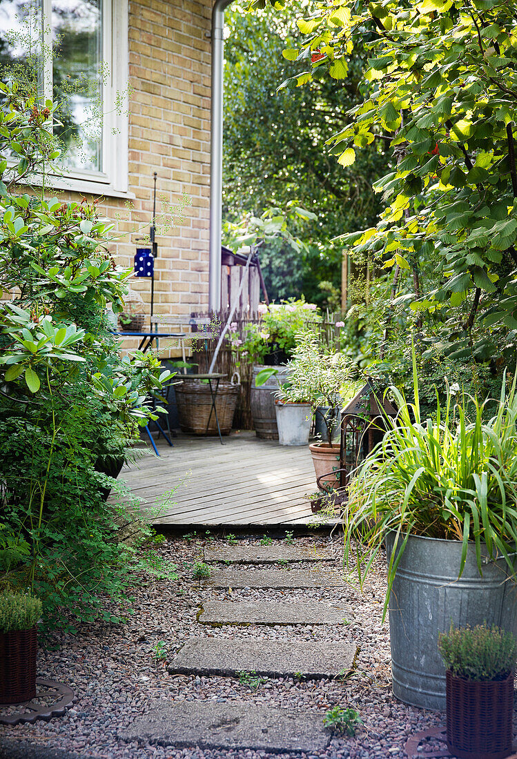 Path with concrete slabs leads to a small wooden terrace