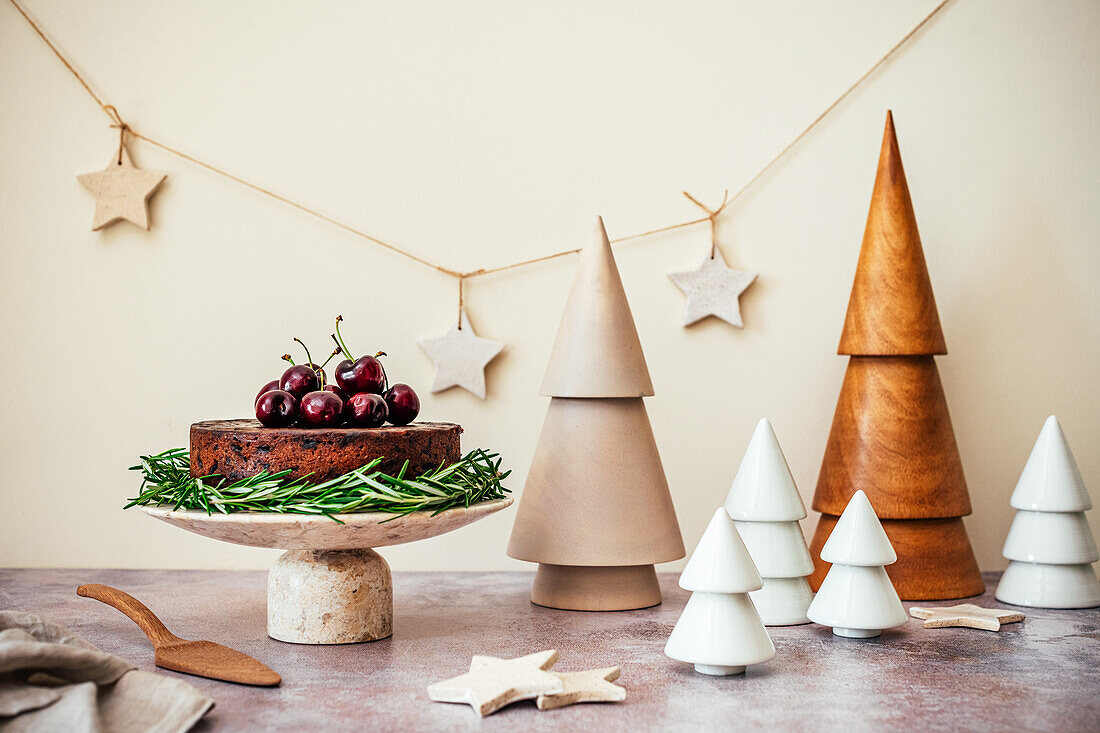 Früchtekuchen mit Kirschen daneben dekorative Weihnachtsbäume aus Holz und Keramik