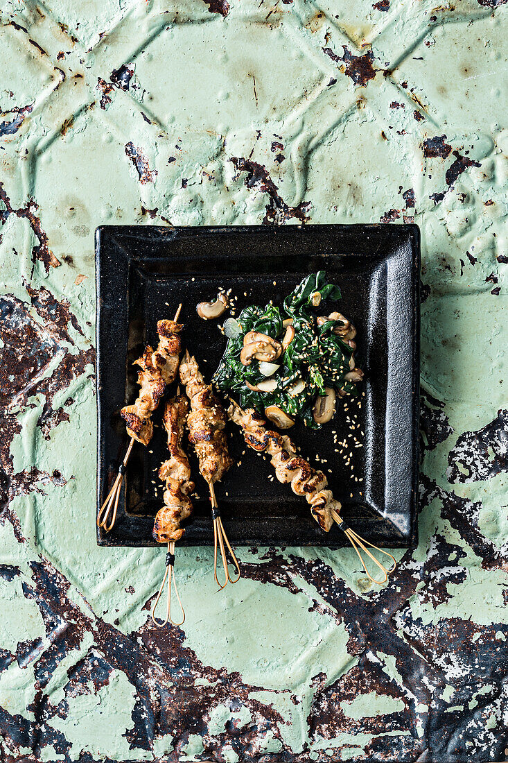 Chicken saté skewers on spinach leaves