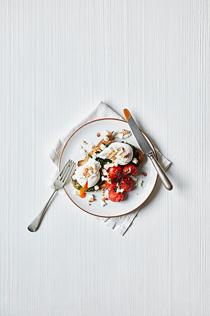 Pochierte Eier mit gebratenen Tomaten und Spinat auf Röstbrot