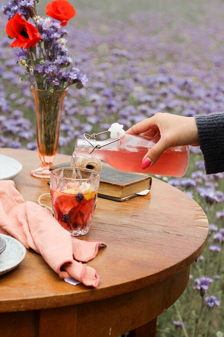 Wild berry lemonade in a glass and a bottle on an outdoor table