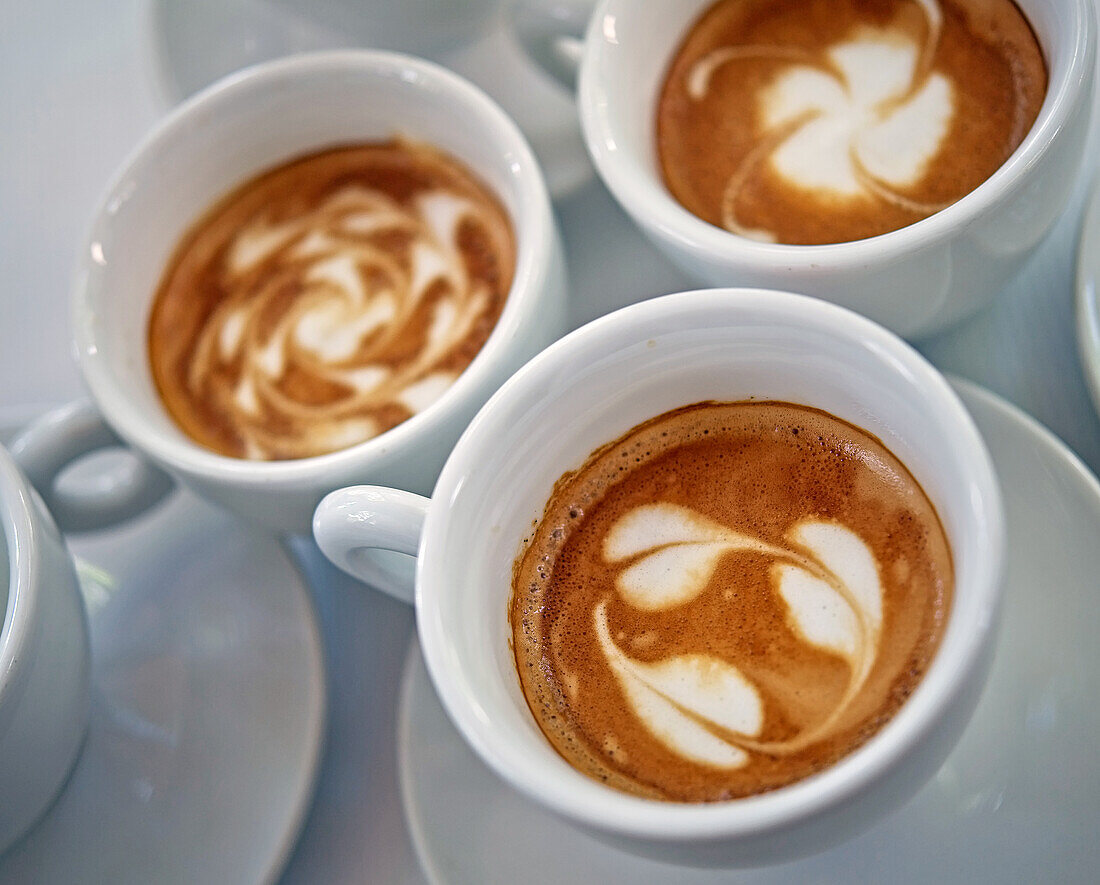 Drei Tassen Cappuccino mit verschiedenen Milchschaummustern