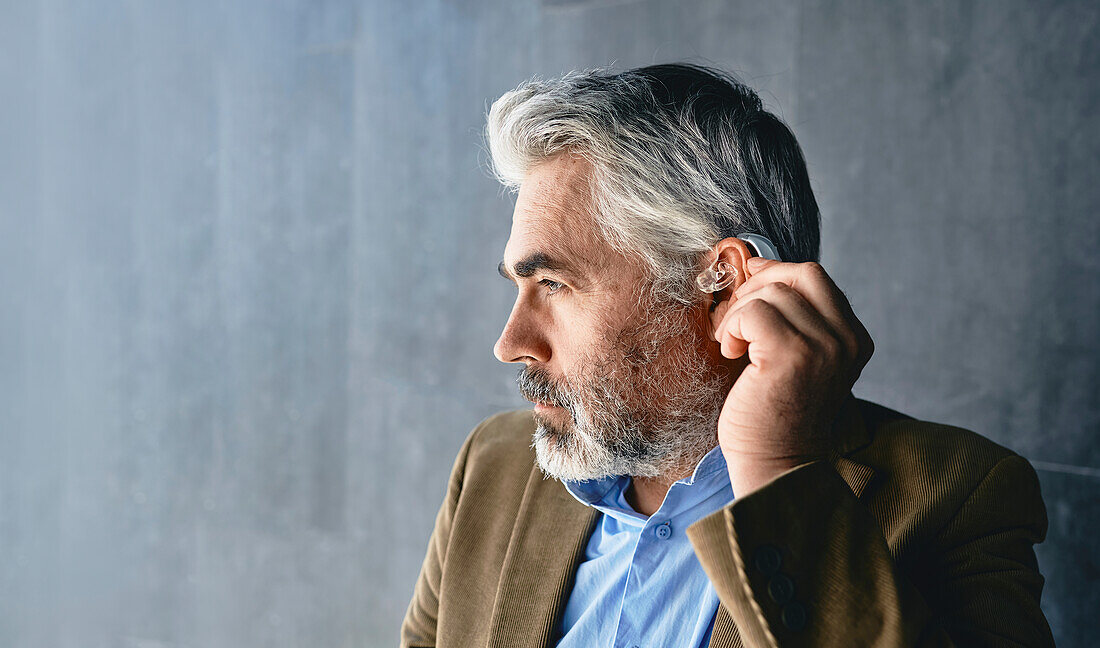 Man adjusting hearing aid