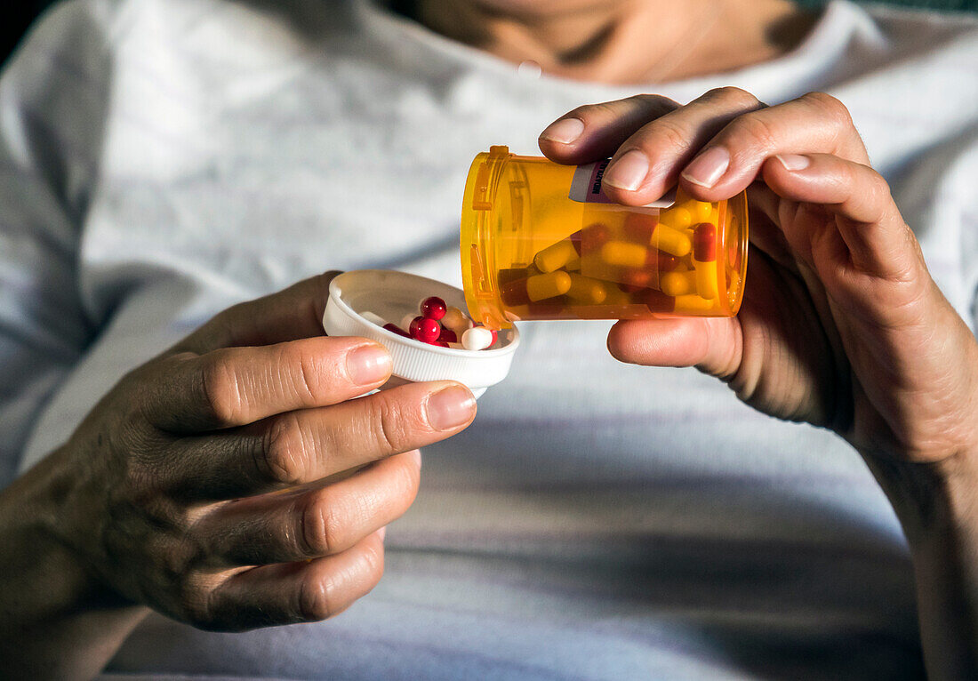 Woman pouring pills into the lid of a medicine bottle