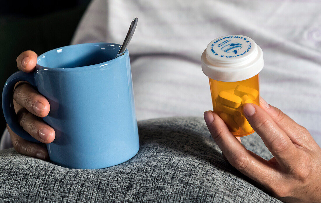 Woman holding a mug and pill bottle
