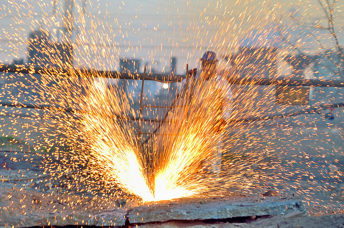 Worker cutting metal with blowtorch