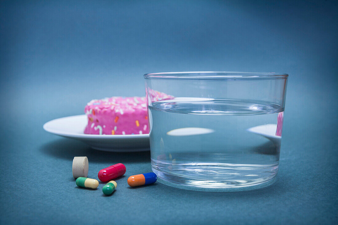 Diabetes medication and a glass of water next to a cake