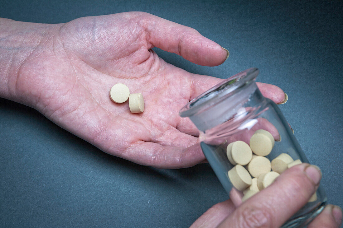 Hand pouring medical pills from a bottle