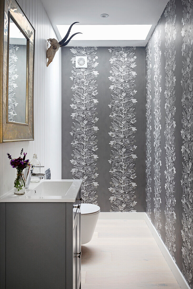 Guest toilet with elegant wallpaper and animal antlers