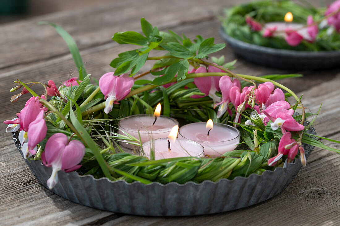 Cake tin with candles and blossoms of the Weeping Heart (Dicentra Spectabilis), still life