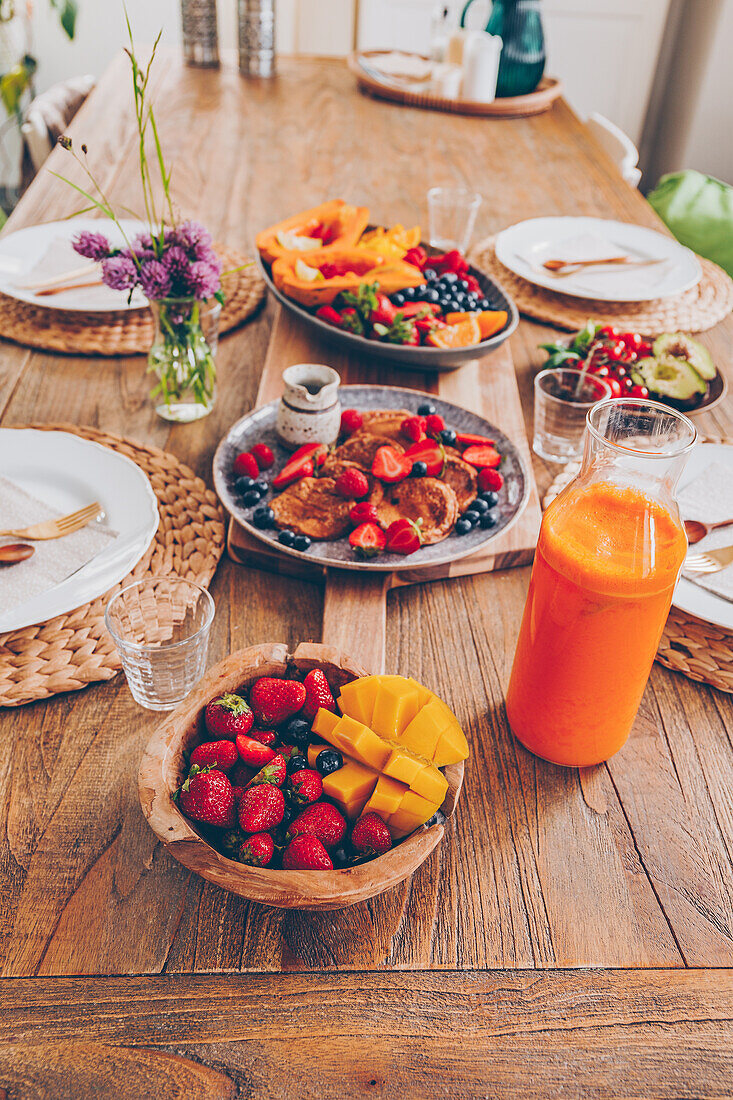 Gesundes Familienfrühstück mit Obst, Mini-Pancakes und Orangen-Karotten-Saft