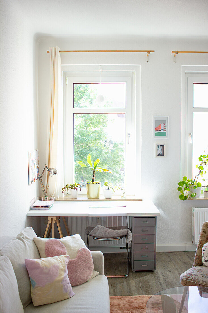 Sofa with cushions and desk under the window in a bright living room