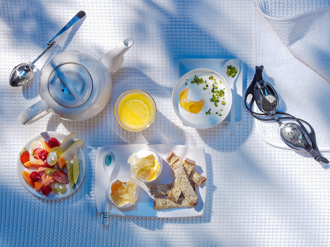 Breakfast with Greek yoghurt, egg, bread, fruit and tea next to a pair of goggles