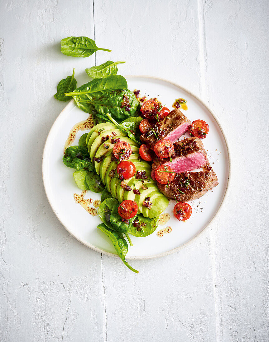 Beef steak with avocado, spinach and tomatoes