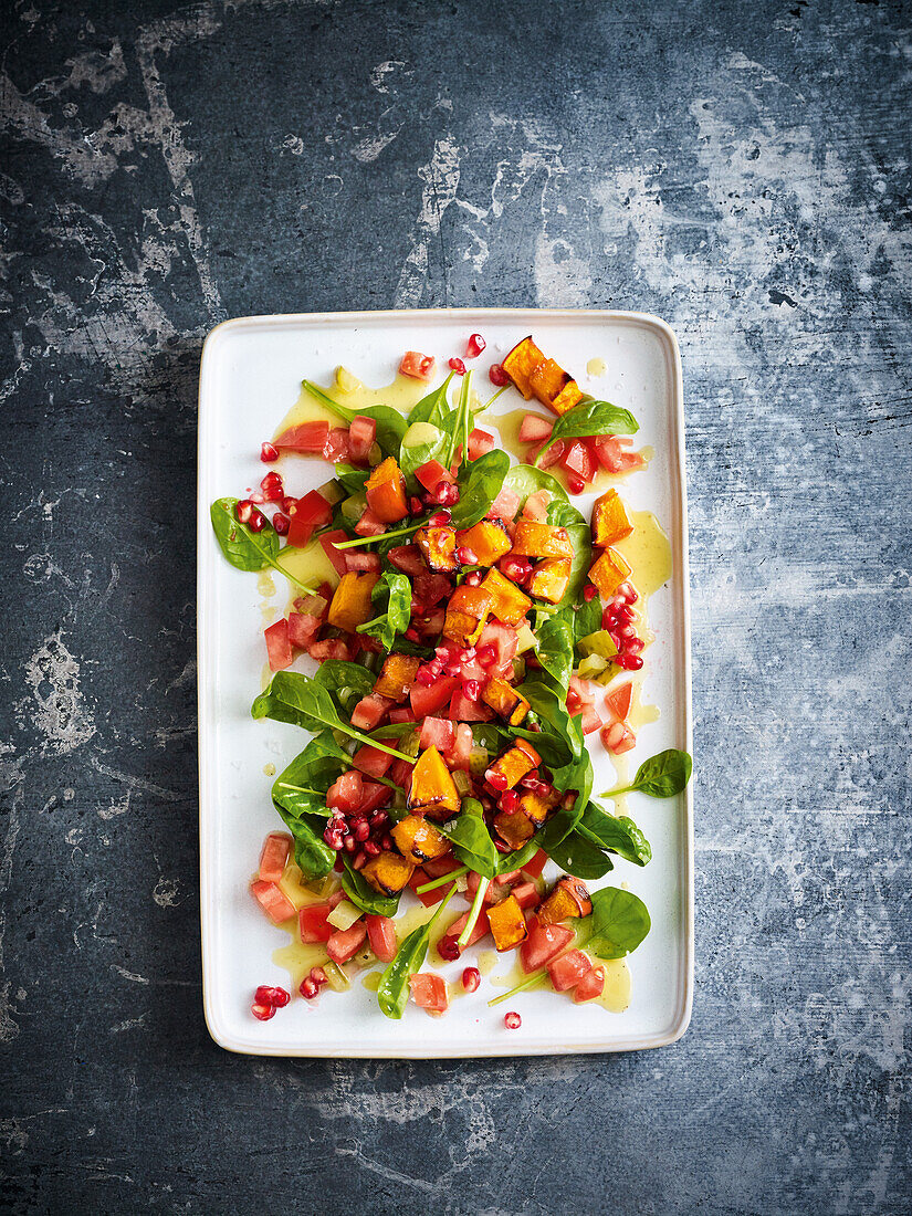 Spinach salad with pumpkin, tomatoes, and pomegranate