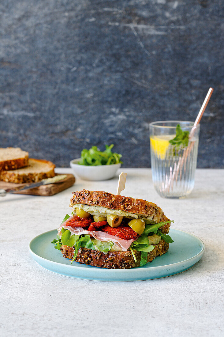 Antipasti sandwich with bean cream, ham, dried tomatoes, and olives