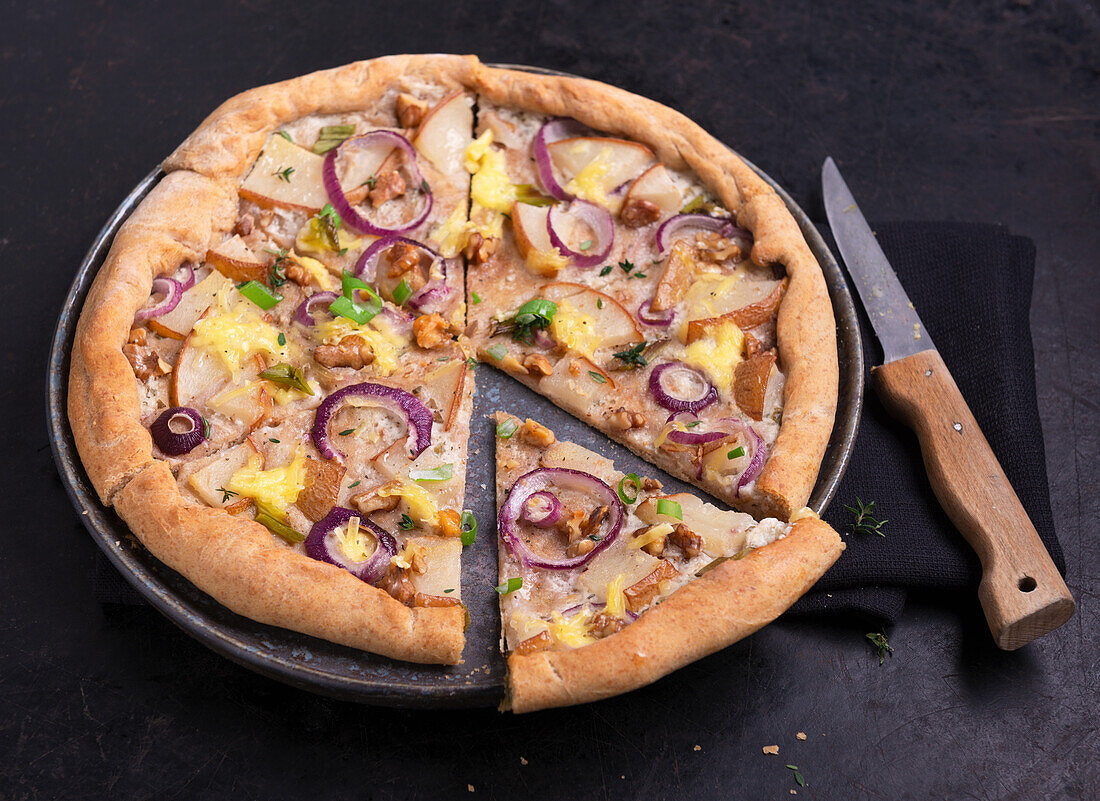Vegane Pizza mit Birnen, Zwiebeln und Walnüssen, angeschnitten