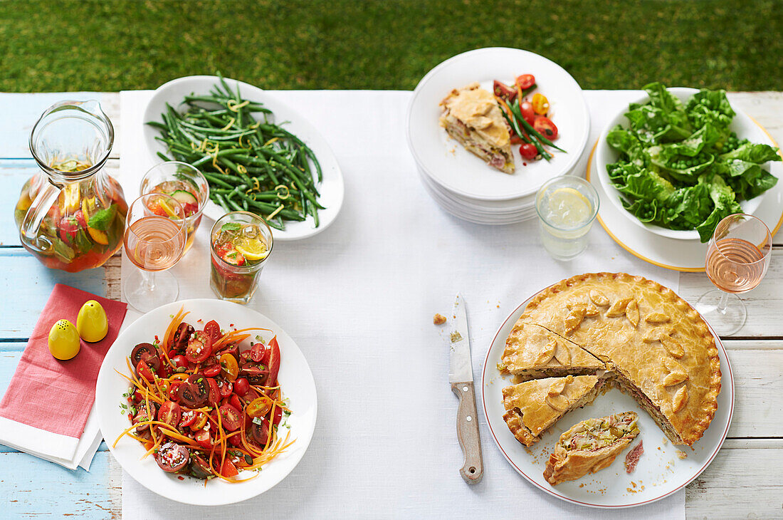 Kartoffel-Schinken-Pie, Blattsalat, Tomaten-Karotten-Salat, grüne Bohnen mit Senf und Limonade