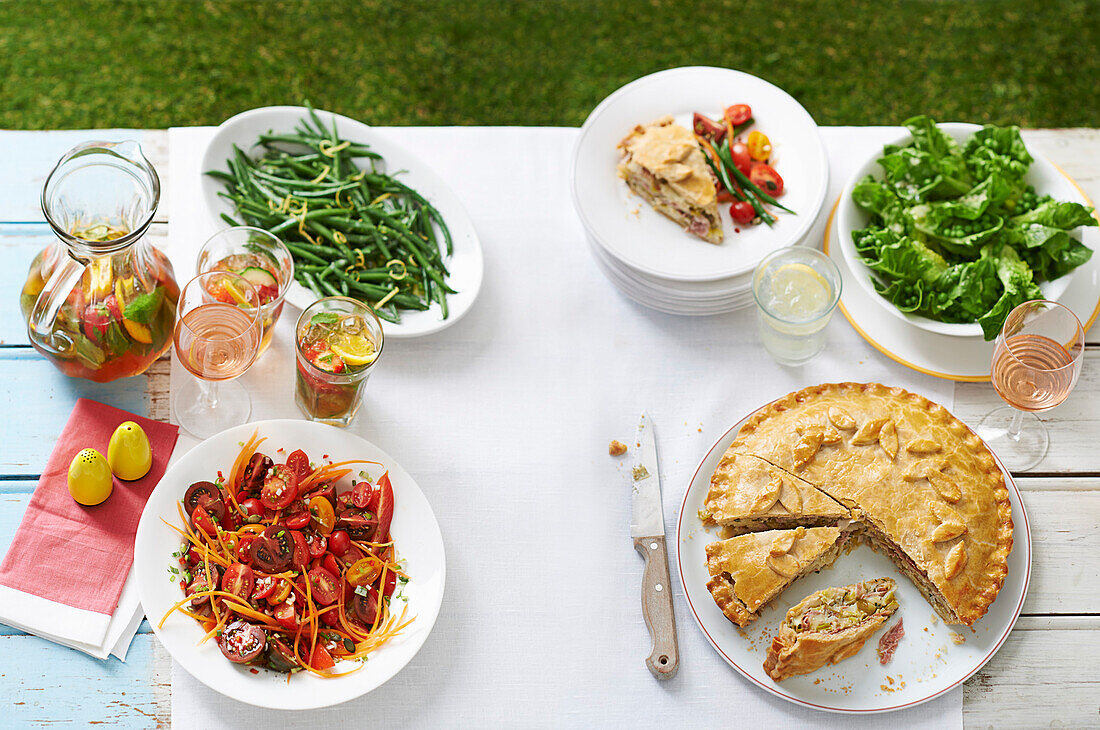 Potato and ham pie, leaf salad, tomato, and carrot salad, green beans with mustard and lemonade