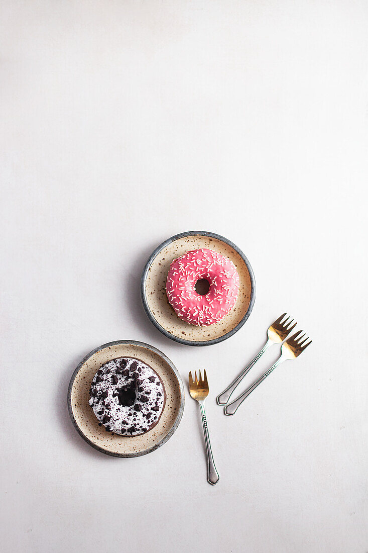 Zwei Donuts, mit Schokostückchen und mit rosa Zuckerglasur