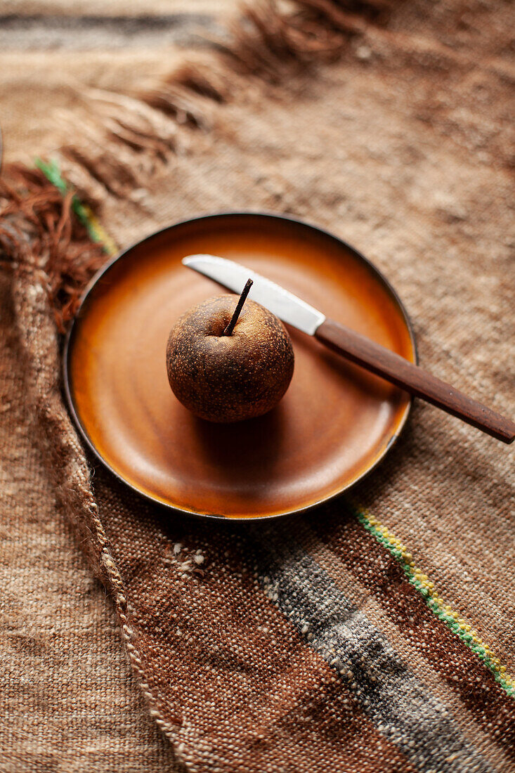 Eine Nashi-Birne mit Messer auf Keramikteller