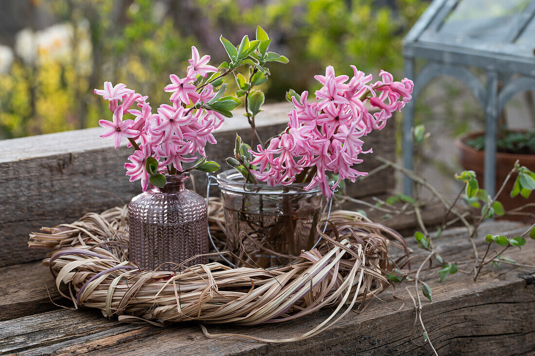 Bouquet of hyacinths in a vase in an Easter wreath on a wooden board